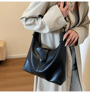 Close-up of a black textured hobo bag worn over the shoulder showing the buckle flap