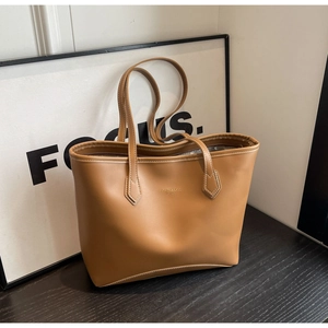 Détail d'un sac cabas en cuir marron avec coutures blanches et logo doré élégant