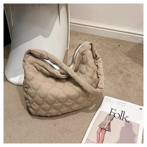 Detail of khaki corduroy tote bag with fish scale quilting on a soft beige carpet