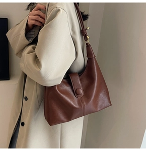 Side view of a dark brown vintage hobo bag on model wearing a beige trench coat