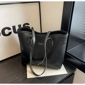 Détail du sac cabas en cuir noir minimaliste avec coutures contrastées et logo doré