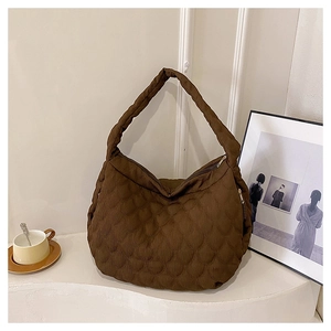 Close-up of brown quilted tote bag featuring glossy fabric and sleek metal zipper detail