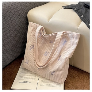 Detail of corduroy tote bag featuring purple letter embroidery and a spacious interior