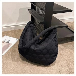Close-up of black wave-quilted tote bag with premium puffy texture and zipper detail