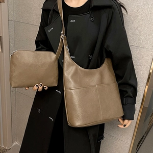 Sac seau marron en cuir avec pochette assortie, porté à l'épaule sur un manteau noir chic
