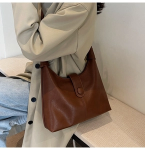 Close-up of caramel brown vintage tote bag featuring knotted strap and flap buckle