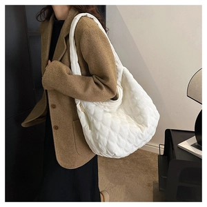 Detail view of the white quilted tote bag texture and integrated wide shoulder strap
