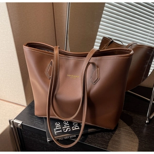 Détail du sac cabas en cuir marron avec surpiqûres blanches et inscription dorée