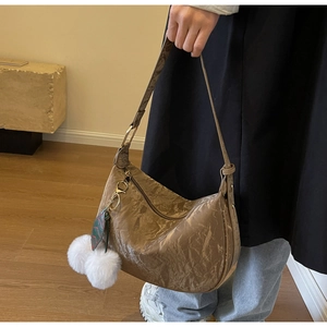 Gros plan du sac en croissant plissé marron avec pendentif en peluche et boucles dorées