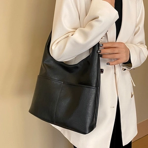 Sac seau minimaliste en cuir PU noir porté épaule avec poche frontale sur un mannequin