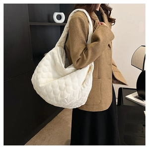 Detail of white quilted half-moon shoulder bag with wave stitching and wide strap