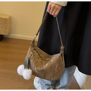 Détail du sac croissant plissé kaki avec boucle en métal et breloque en peluche