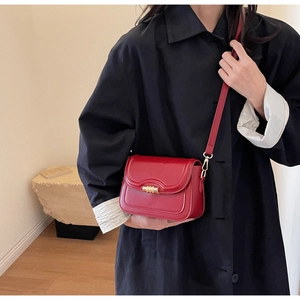 Close-up of red saddle bag with wave edge design and golden buckle on model