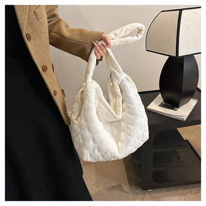 Close-up of white quilted corduroy tote bag showing textured diamond pattern and gold zipper