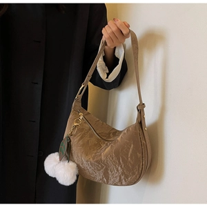 Détail du sac demi-lune plissé marron avec breloques feuille et pompon sur modèle