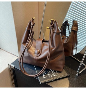 Close-up of a dark brown leather hobo bag with a unique knotted shoulder strap detail
