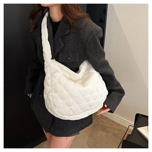 Detailed close-up of a white quilted tote bag worn with a gray blazer for a modern look