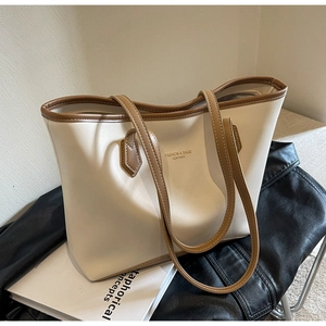 Détail d'un sac cabas beige et marron mis en scène avec une veste en cuir et un livre