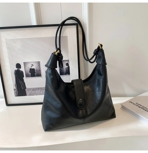 Detail of black vintage hobo bag with knotted straps and polished metallic rings