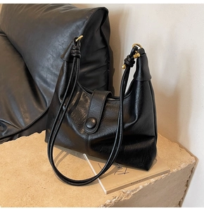 Close-up of black pebbled leather hobo bag with gold hardware and rope straps
