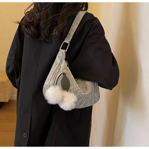 Détail de la texture argentée plissée du sac demi-lune avec pompons blancs et décor