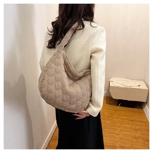 Detail of khaki quilted crescent bag showing scale-pattern texture and padded strap
