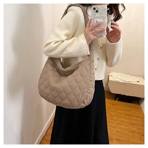 Close-up of beige quilted tote bag with shell patterns and a wide shoulder strap