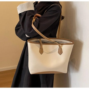 Détail du sac fourre-tout blanc crème avec bordure en cuir marron et texte imprimé