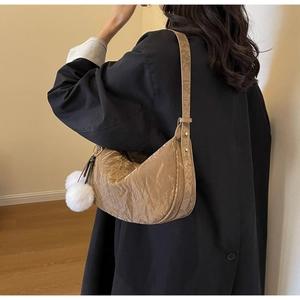 Détail d'un sac hobo marron texturé avec breloque en peluche blanche et boucle dorée