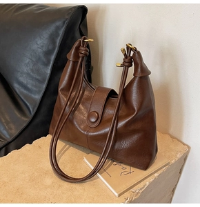 Detail of vintage brown tote bag showing magnetic closure and knotted shoulder strap