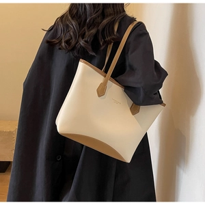 Grand sac cabas en cuir beige et marron porté à l'épaule dans un cadre moderne