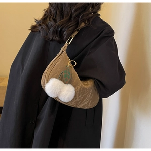 Gros plan d'un sac à bandoulière marron gaufré avec un charmant pendentif cerise en peluche