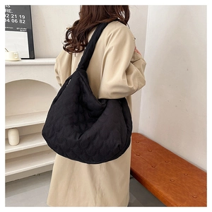 Large black quilted tote bag with unique fish scale pattern shown on a female model