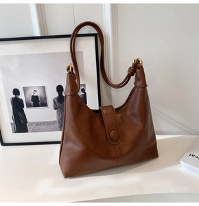 Close-up of brown vintage leather tote with metal buckle and golden ring details