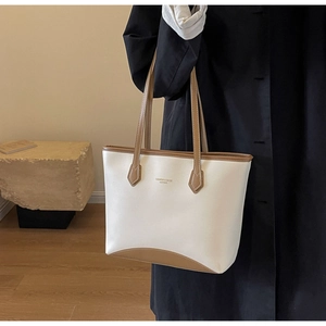 Détail d'un sac cabas en cuir bicolore avec texte imprimé et coutures élégantes