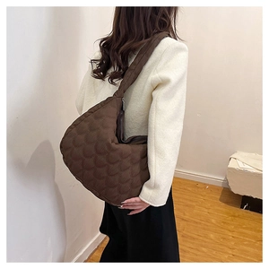Detail of dark brown quilted tote bag showing wave stitching texture and wide strap