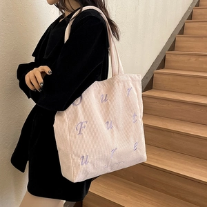 Pink corduroy tote bag with purple Future embroidery shown on wooden stairs