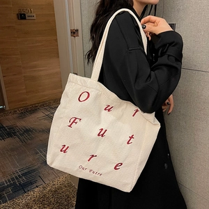 White corduroy tote bag with red 'Our Future' embroidery shown on model for commuting
