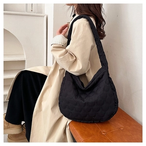 Quilted black tote bag with wave stitching shown on a model in a minimalist studio setting
