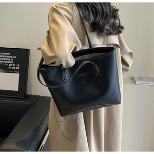 Détail d'un grand sac cabas en cuir noir avec coutures blanches porté par un mannequin