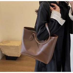 Détail d'un sac cabas en cuir marron foncé avec coutures contrastées et lettrage doré