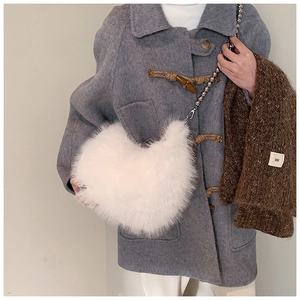 Détail d'un sac bandoulière en peluche blanche avec une chaîne à boules argentées douce