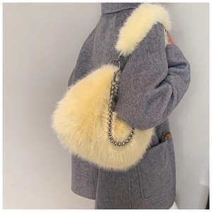 Détail du sac seau en fausse fourrure jaune pâle avec chaîne perlée sur manteau gris