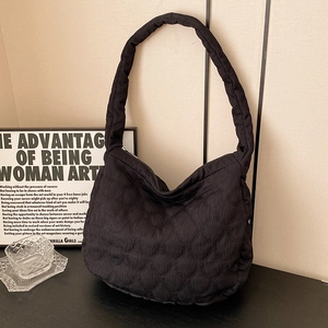 Black quilted hobo tote bag with padded strap and silver zipper in a modern setting