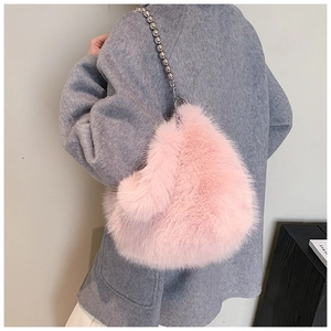 Détail du sac seau en fausse fourrure rose avec chaîne à billes argentées sur manteau gris