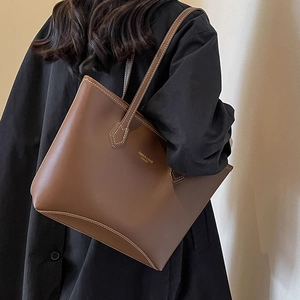 Sac fourre-tout en cuir marron avec coutures contrastées porté par un mannequin