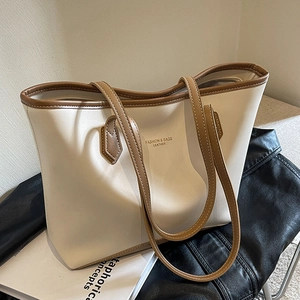 Grand sac cabas Maillard en cuir crème et marron sur une table avec veste noire