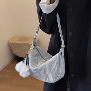 Sac hobo argenté métallisé avec texture plissée et breloque en peluche blanche porté