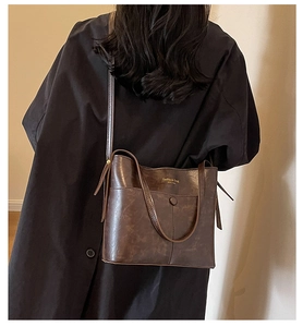 Close-up of vintage dark brown bucket bag with gold lettering and textured leather