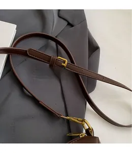 Detail of adjustable dark brown leather shoulder strap with gold metal lobster clasp